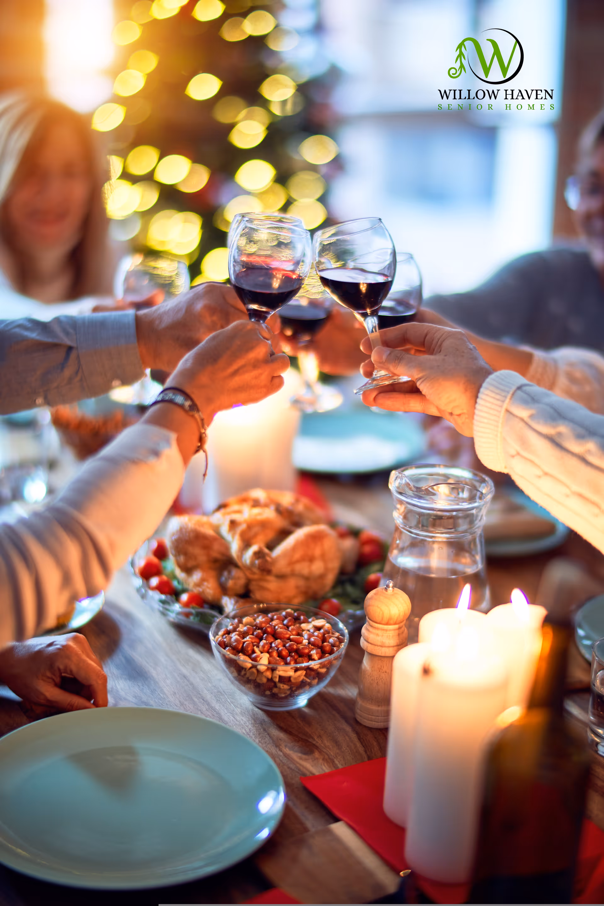 A group of people raising glasses of red wine in a toast around a dining table set with a roasted chicken, a bowl of nuts, candles, and a pitcher of water, with festive lights in the background.