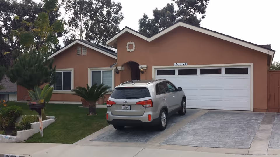 Front exterior of a single-story care facility with a driveway, SUV, and two-car garage.