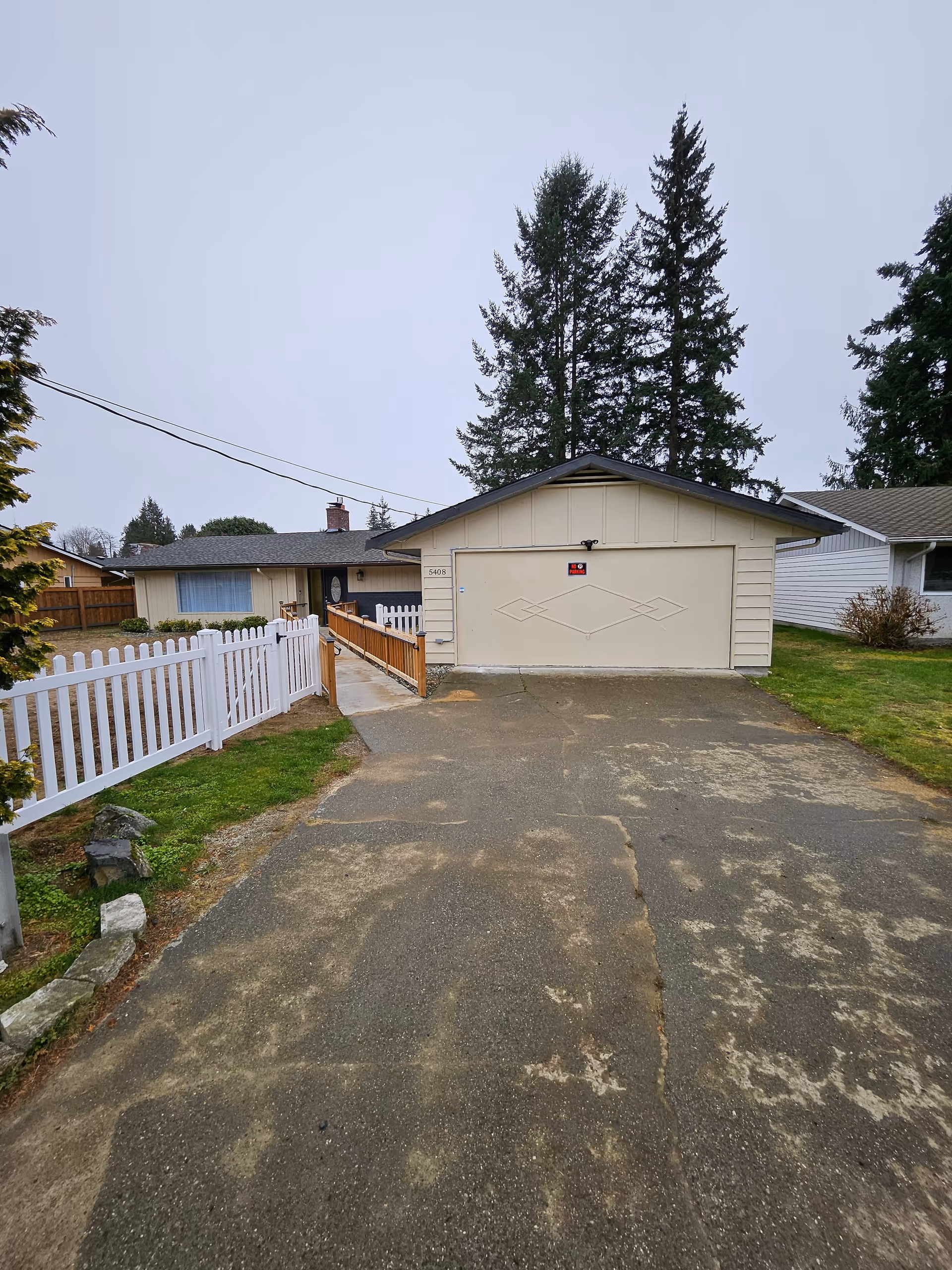 Front view of a single-story home with a white fence and garage.