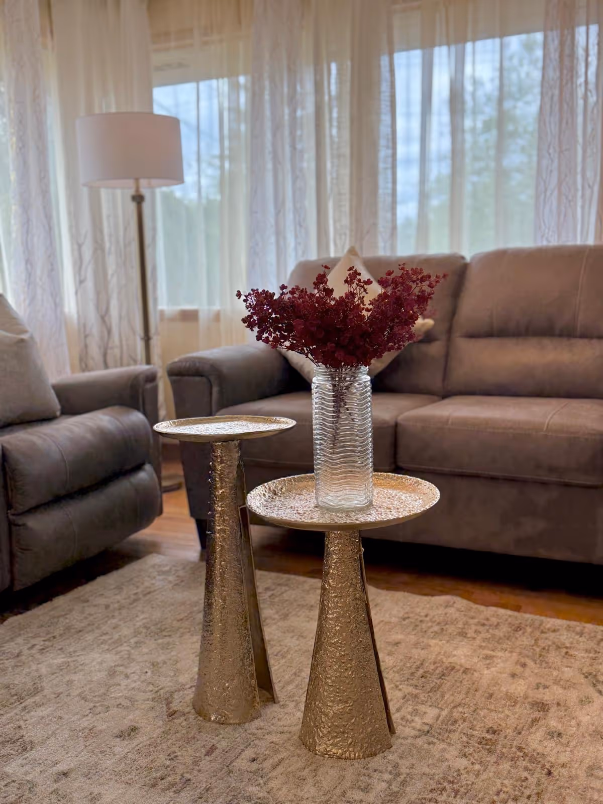 Cozy living room with gray sofas, gold tables, and purple dried flowers.