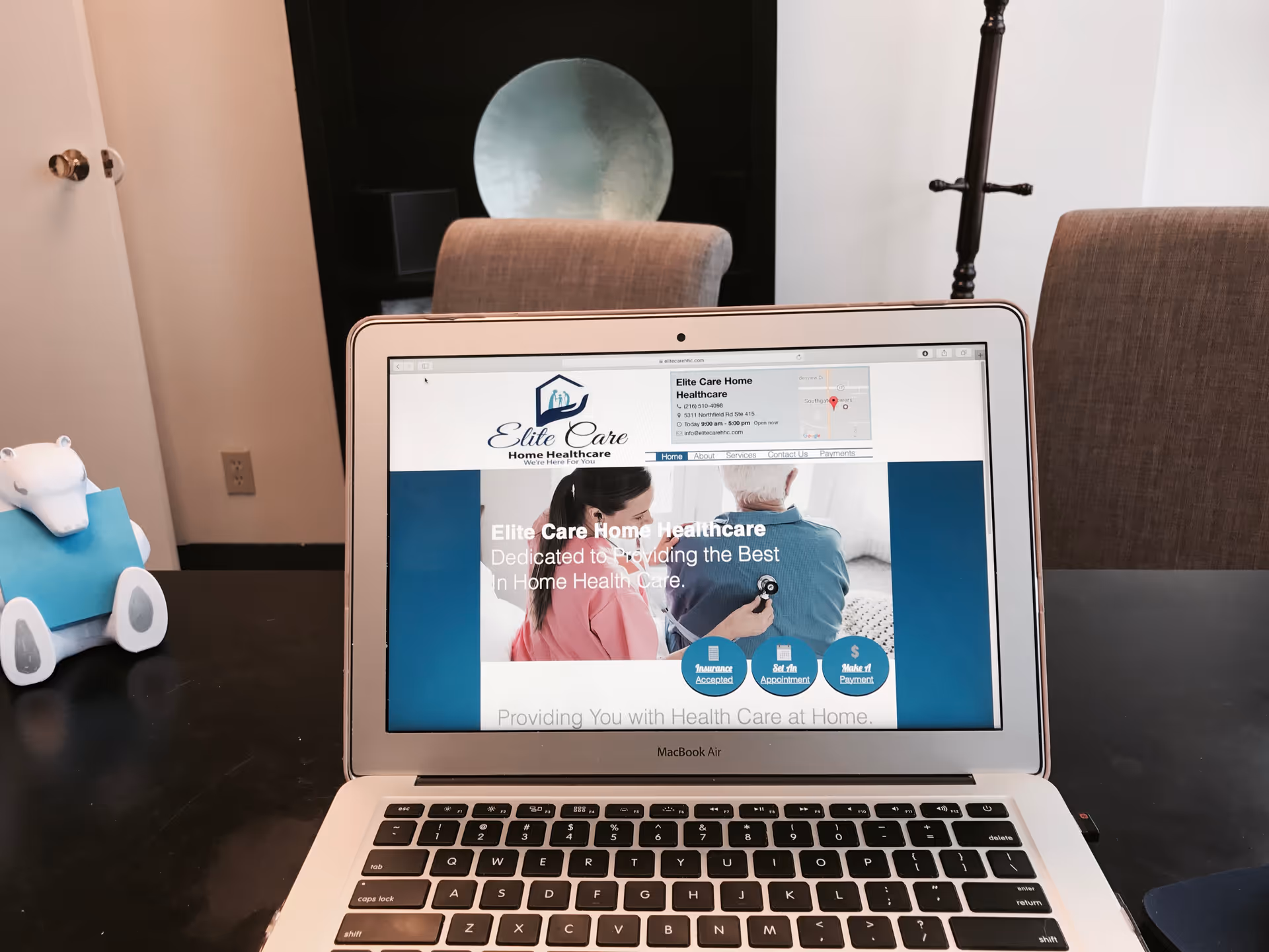 Open laptop on a dark table displaying Elite Care Home Healthcare website.