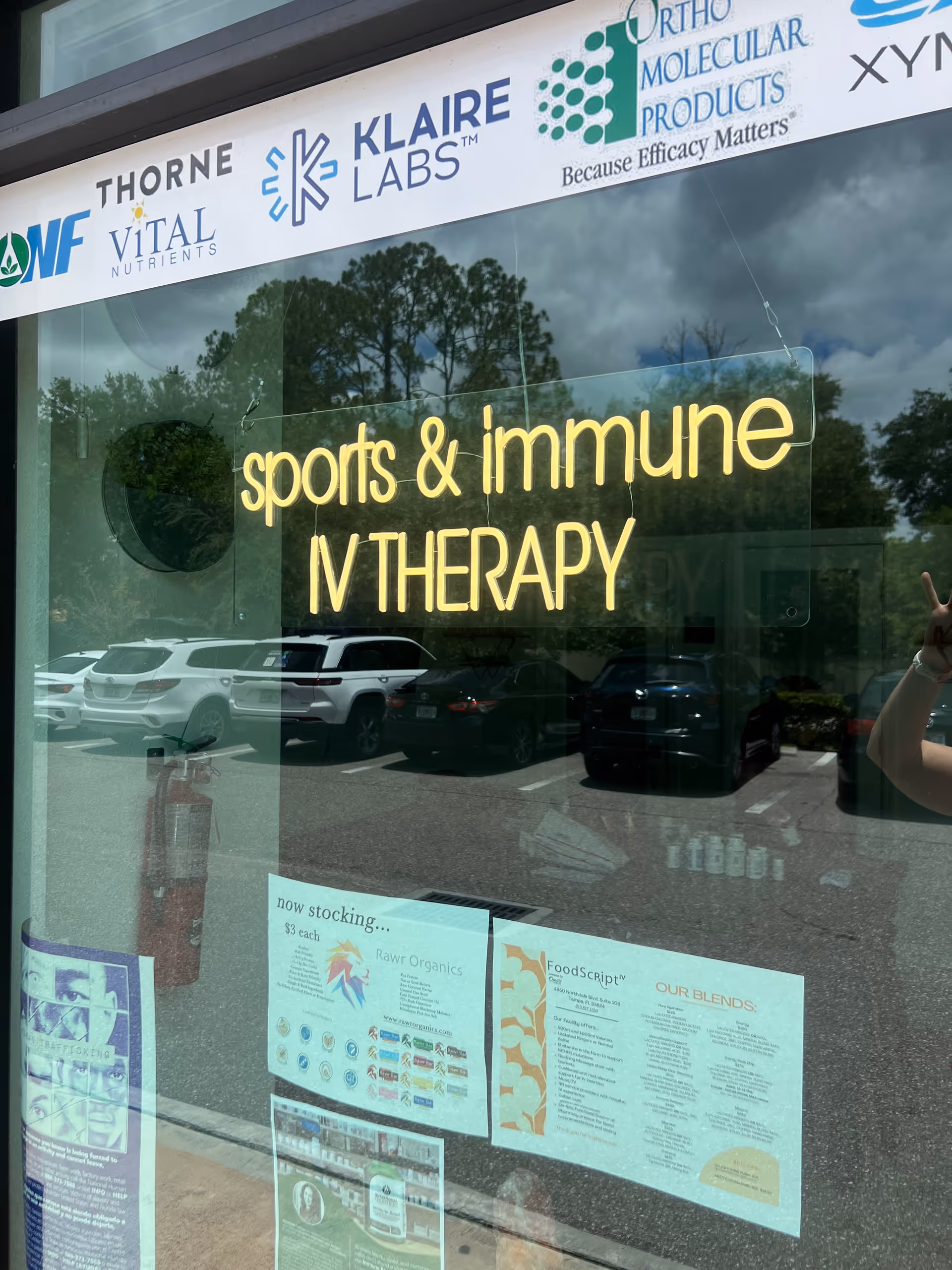 A storefront window shows a neon IV THERAPY sign and brand logos.
