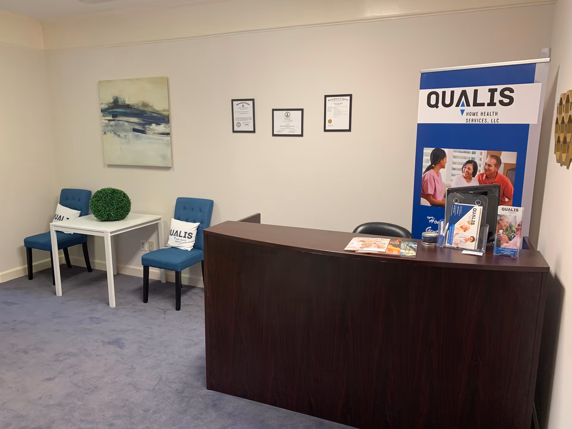 Reception desk with a banner, two blue chairs, and brochures in a waiting area.