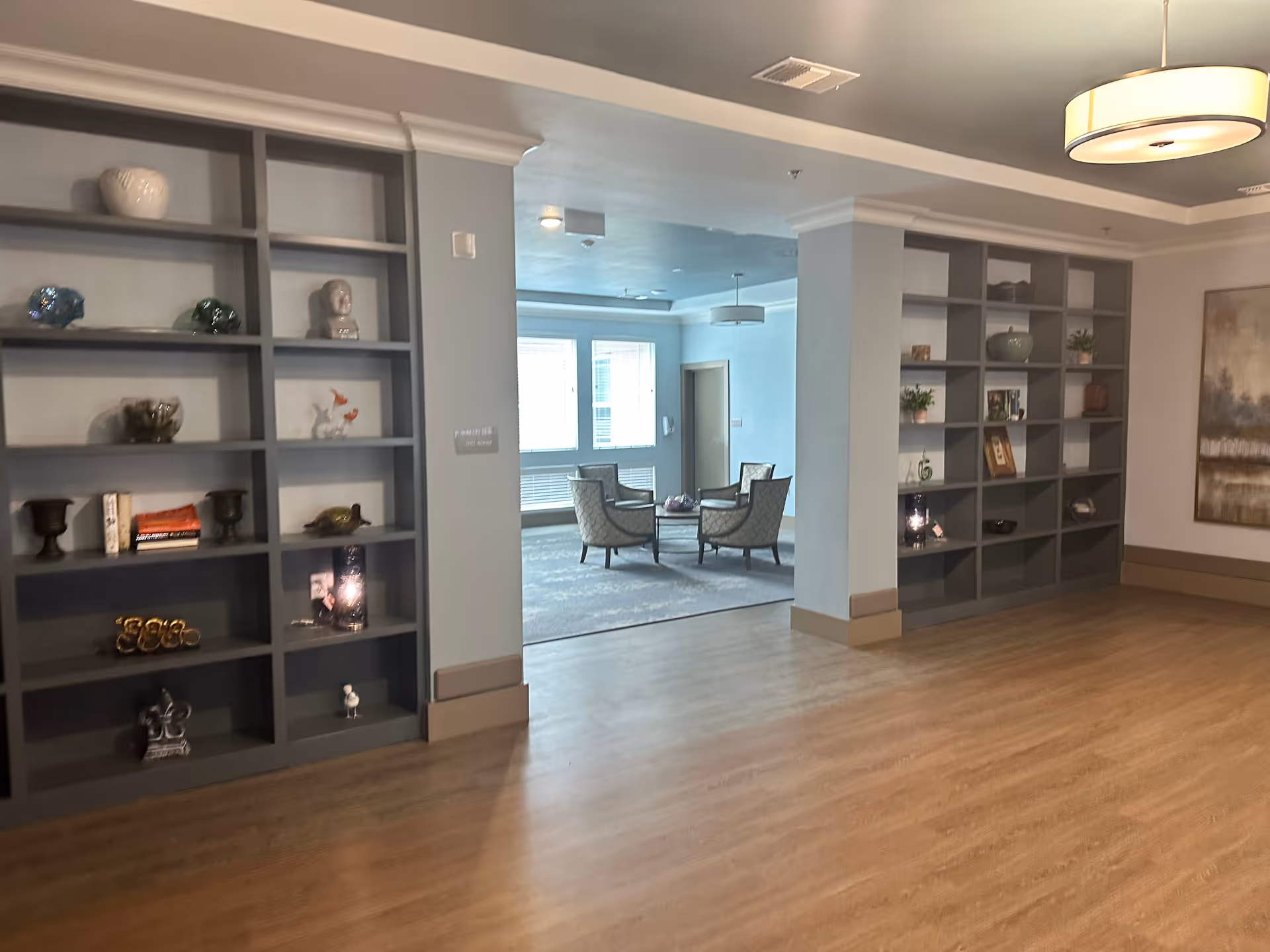 Interior lobby featuring tall gray bookshelves, decorative items, and a central seating area.