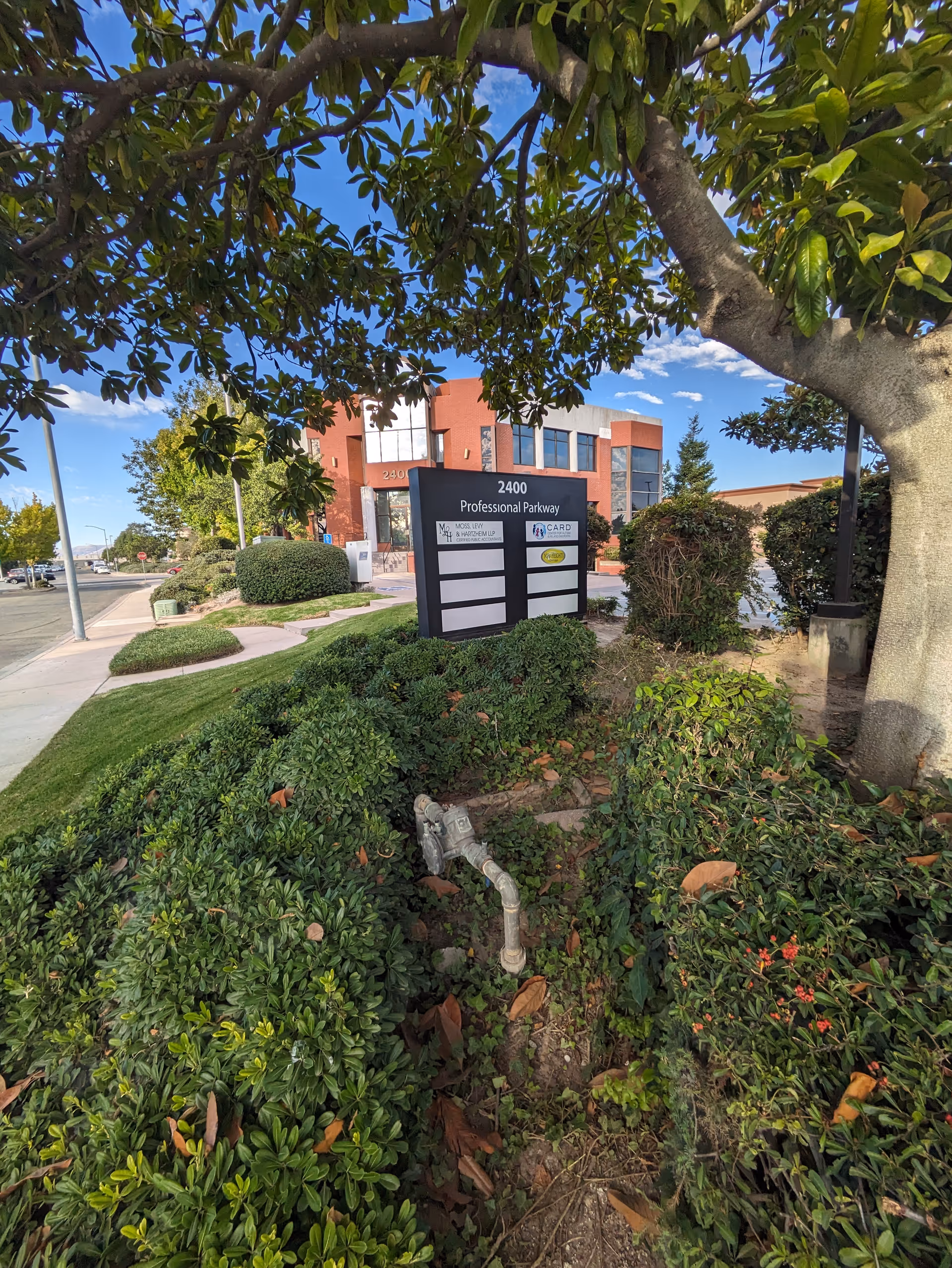 Exterior view of a brick building with a front sign and manicured landscaping.