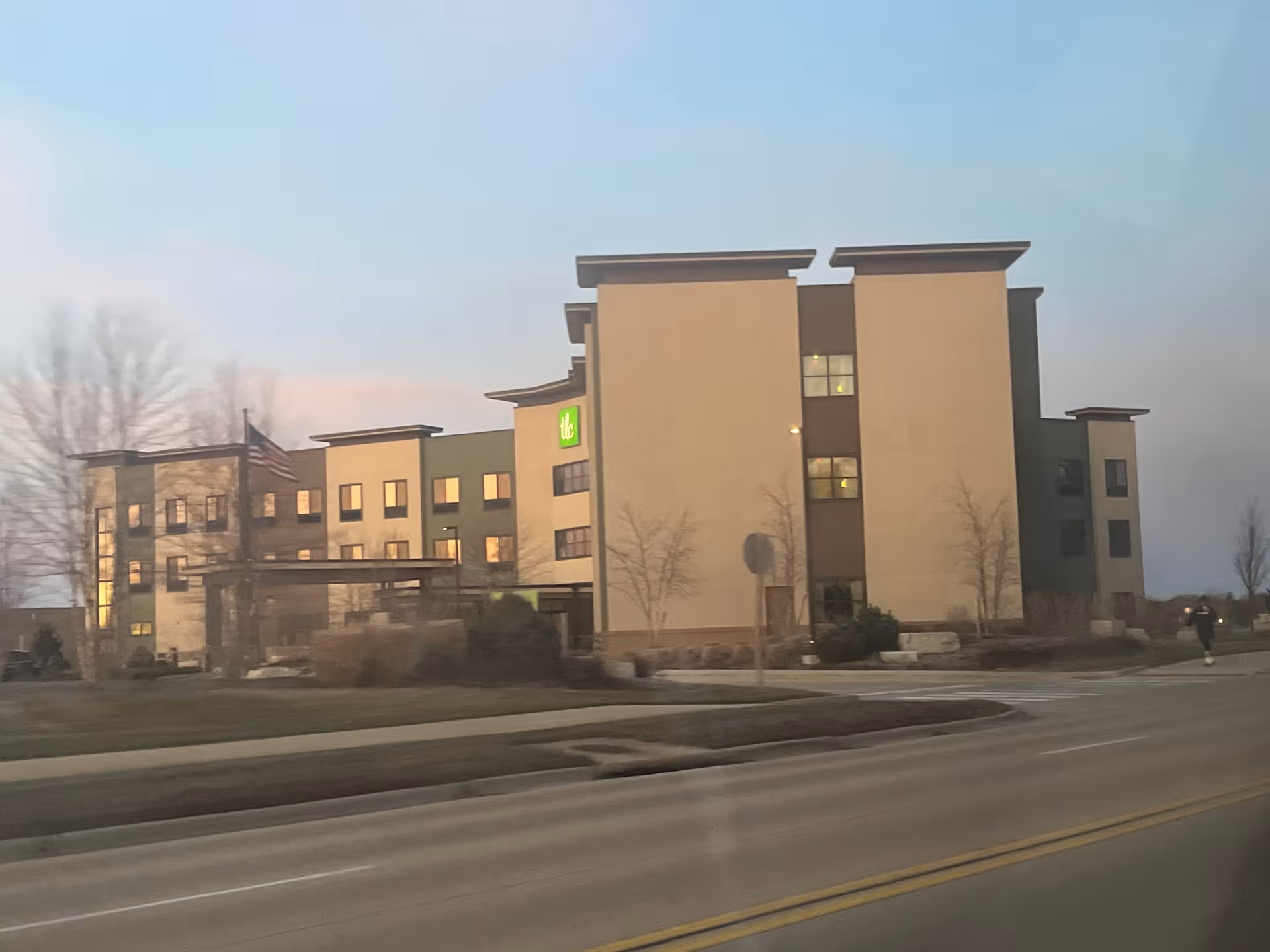 Exterior view of a TLC Living Community building along a street with landscaping.