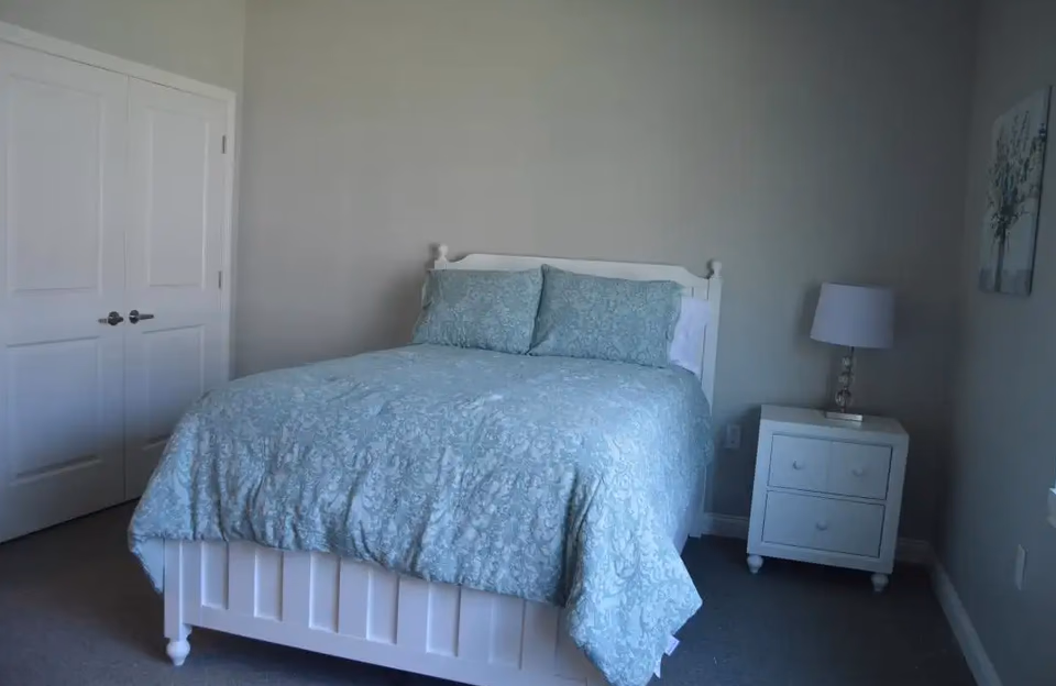 White bed with blue patterned bedding and bedside table in a cozy bedroom.