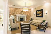 Cozy living room with a stone fireplace, beige seating, and framed art.
