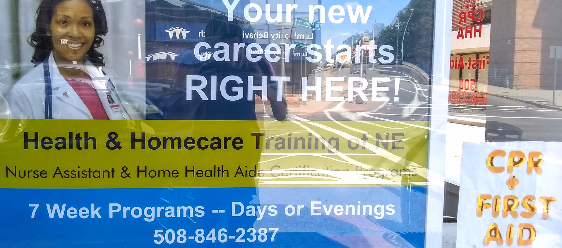 Nurse training advertisement on a window features a smiling staff member in a white coat.