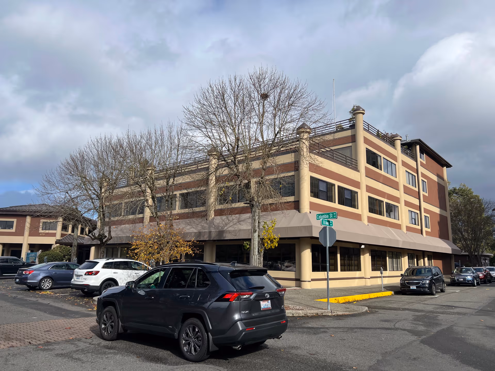 Three-story Weatherly Inn senior living building with large windows and parked cars along street