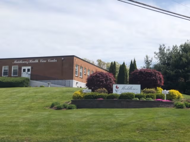 Exterior view of Middlesex Health Care Center with manicured lawn and sign