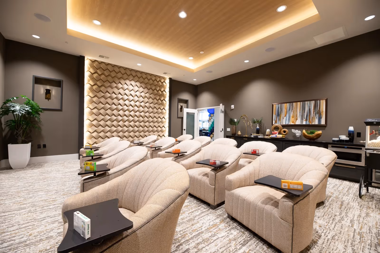 A modern lounge area with several comfortable chairs and side tables, decorated with plants and artwork.