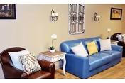 A cozy living room seating area with a blue couch, brown chair, and side table.