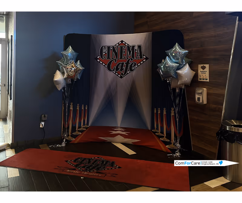 Indoor event setup with Cinema Cafe backdrop, red carpet, balloons, and stanchions.