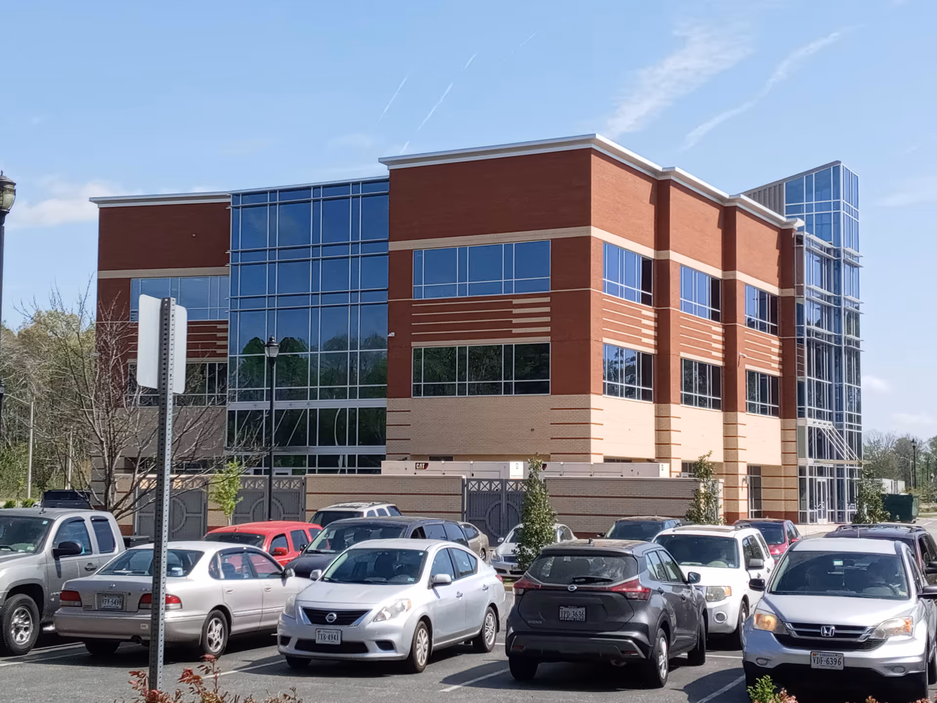 Exterior view of a modern brick-and-glass senior facility with a parking lot.