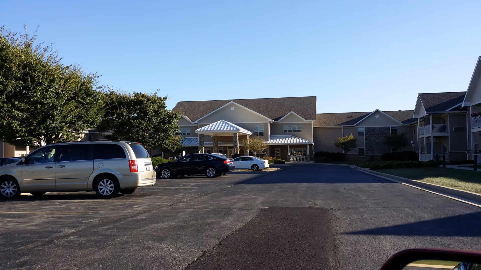 Front view of Primrose Retirement Community of Decatur with parked cars and clear sky.