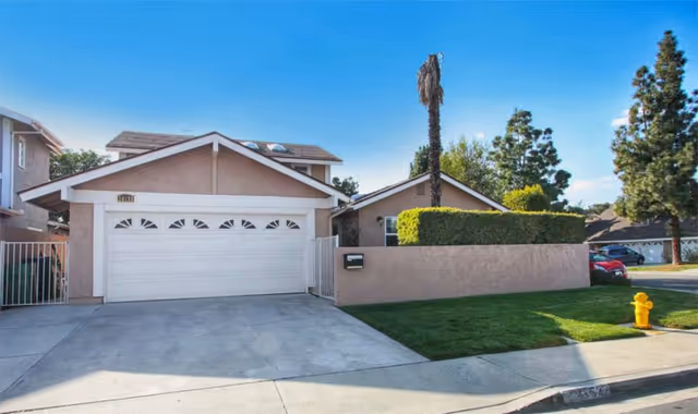 Front view of a beige, single-story house with a two-car garage.