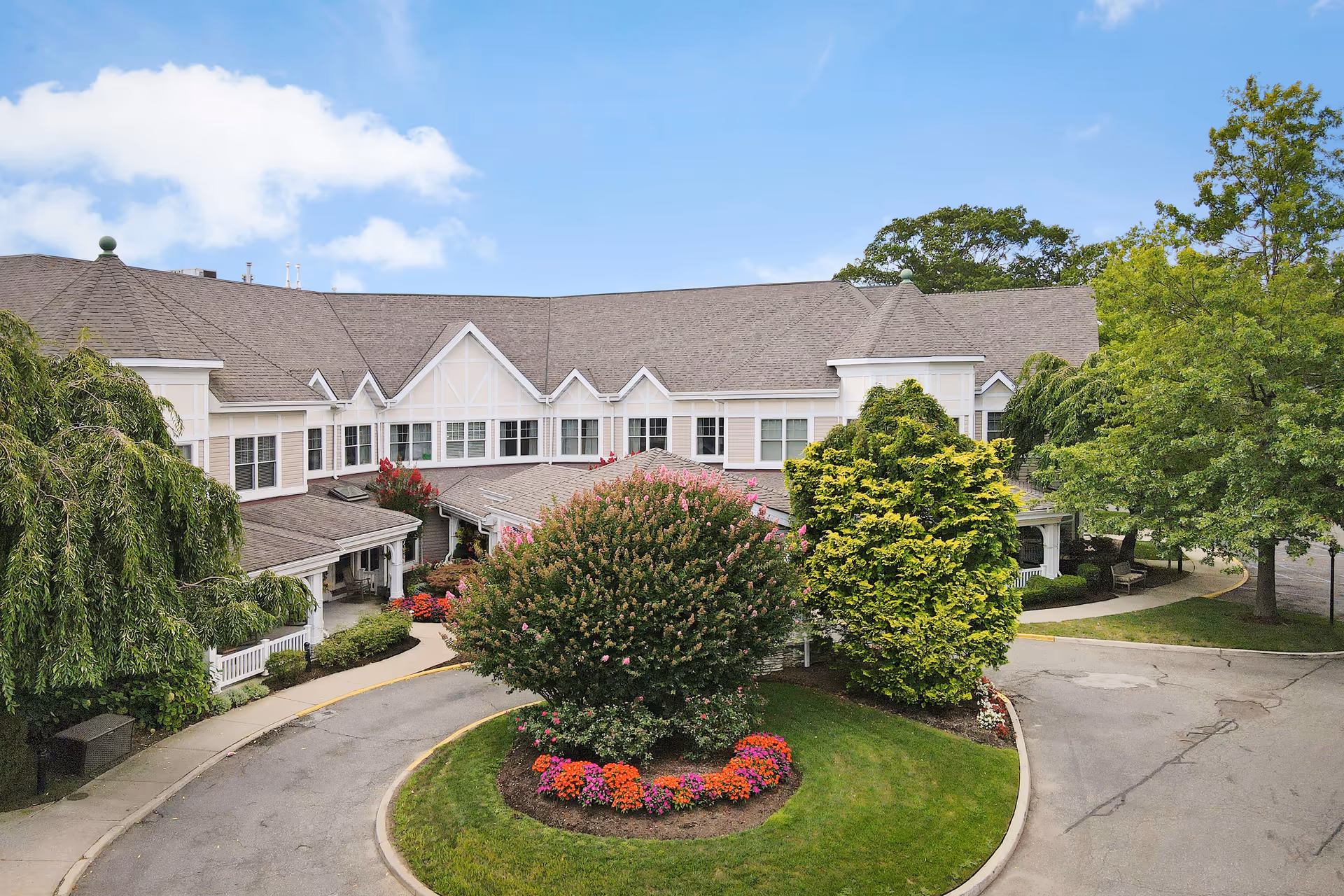 An exterior view of Sunrise of North Lynbrook with a circular landscaped driveway.