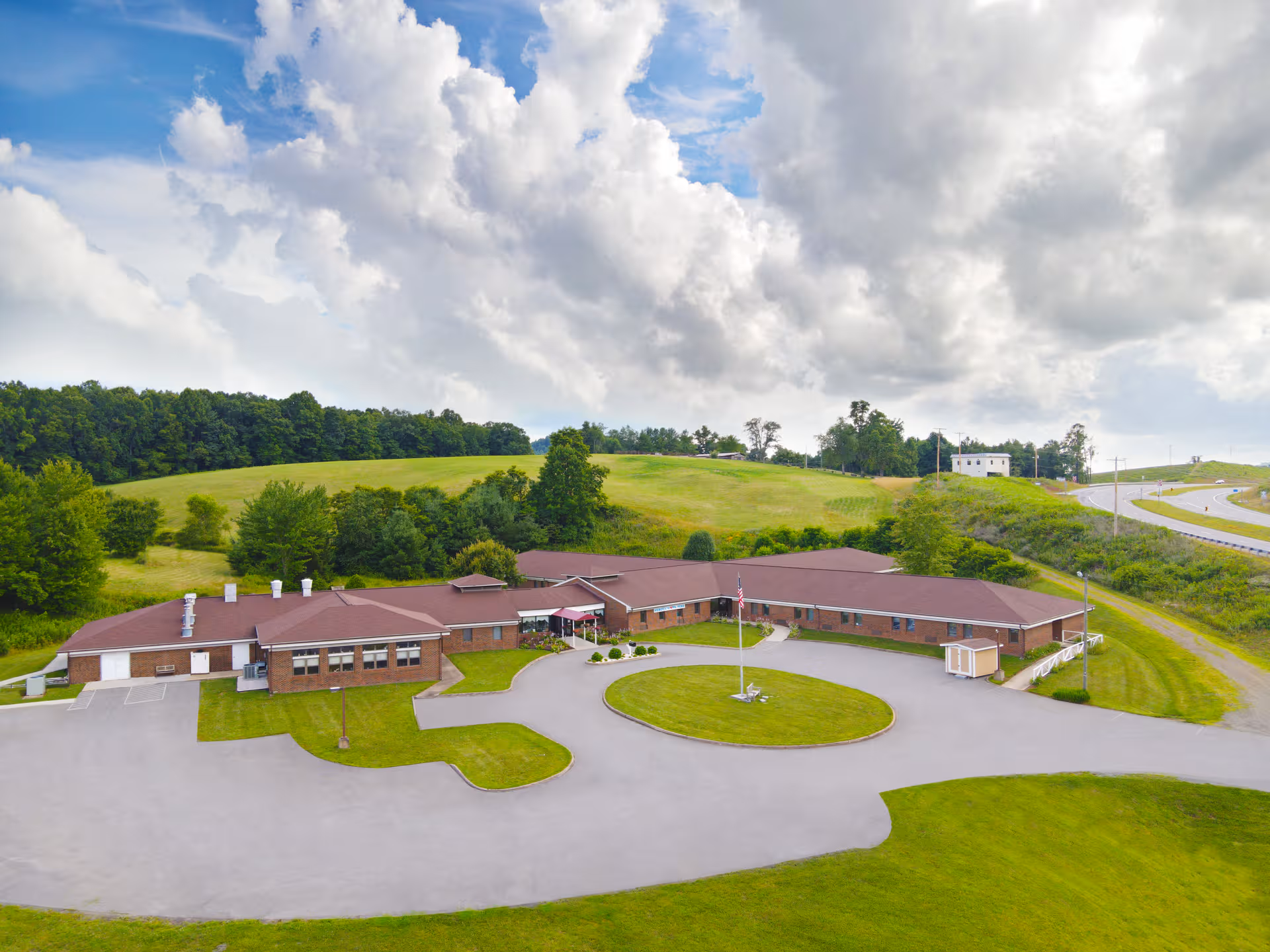 A single-story brick facility sits in a grassy landscape with a circular driveway.