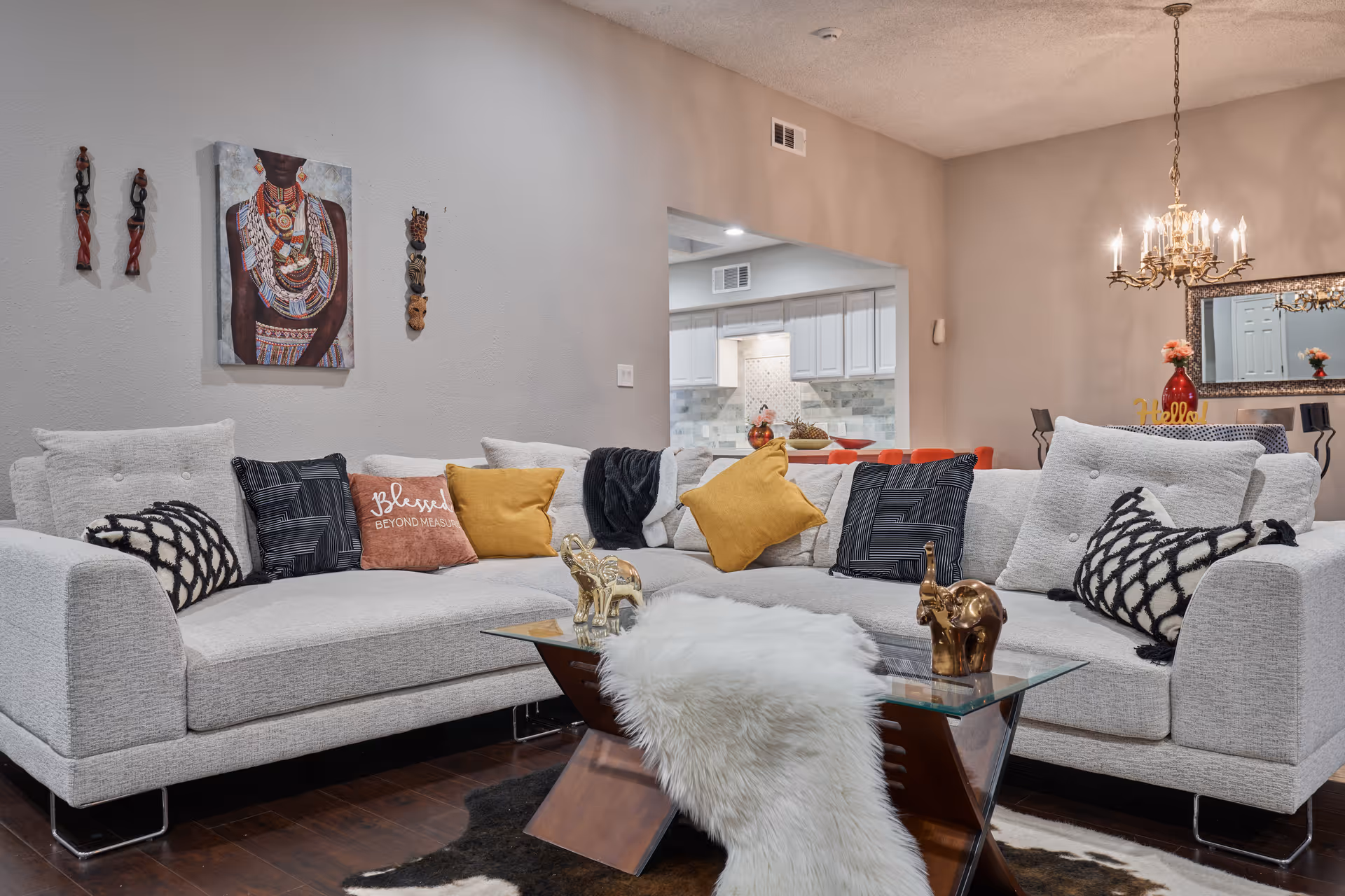 A spacious living room with a large white sectional, decorative throw pillows, and glass coffee table.