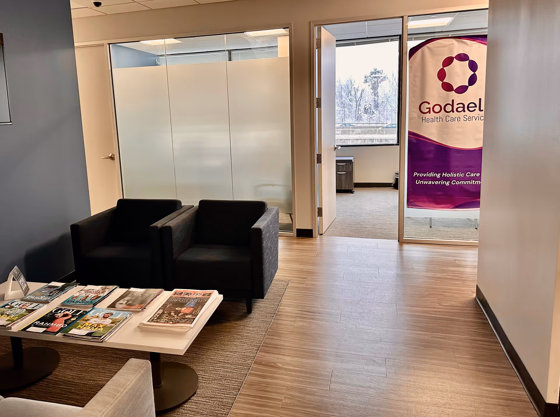 A modern waiting area with black chairs, magazines, and a Godaeli banner.