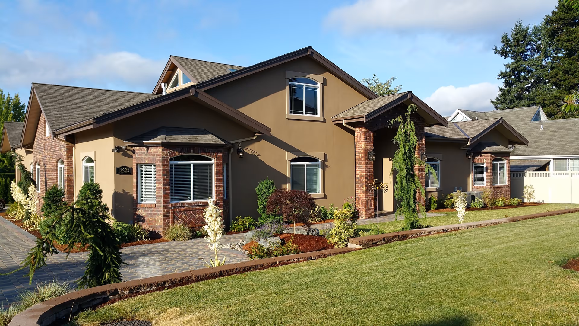 A single-story senior living facility with brown stucco and brick exterior, landscaped front yard and walkway.
