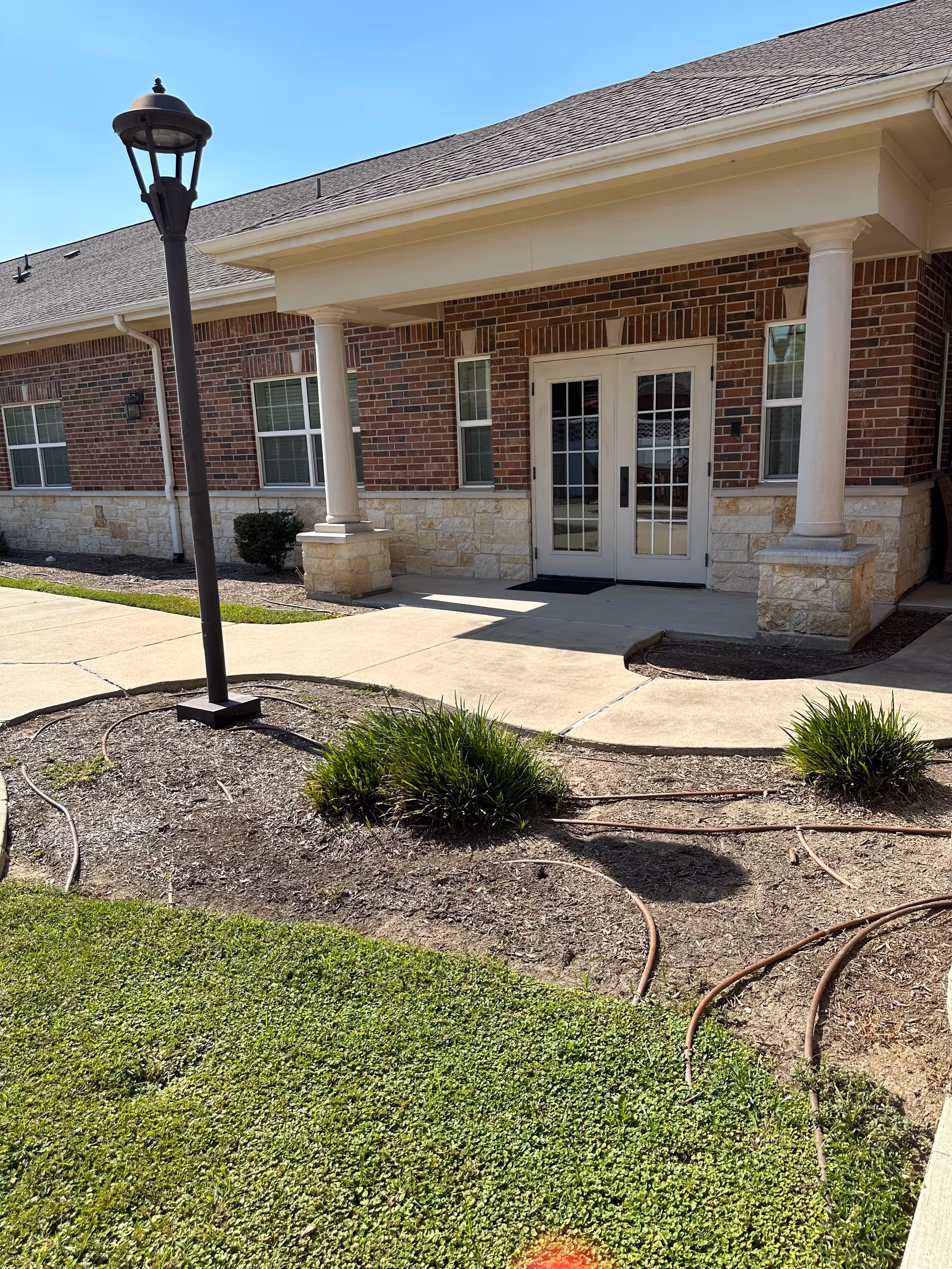 Willow Fork Alzheimer's Care Center entrance: brick exterior, white double doors, columns, lamp post, landscaped front.