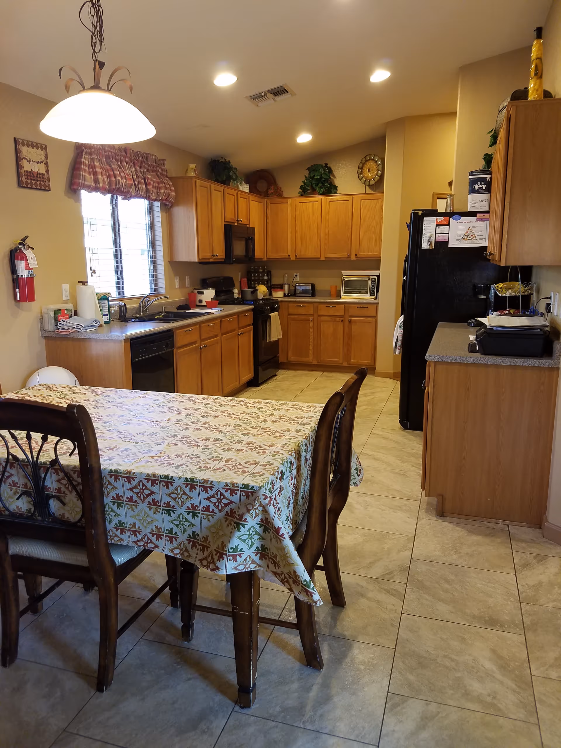 Sunlit dining area adjacent to a full kitchen, with table, chairs, and cabinets.