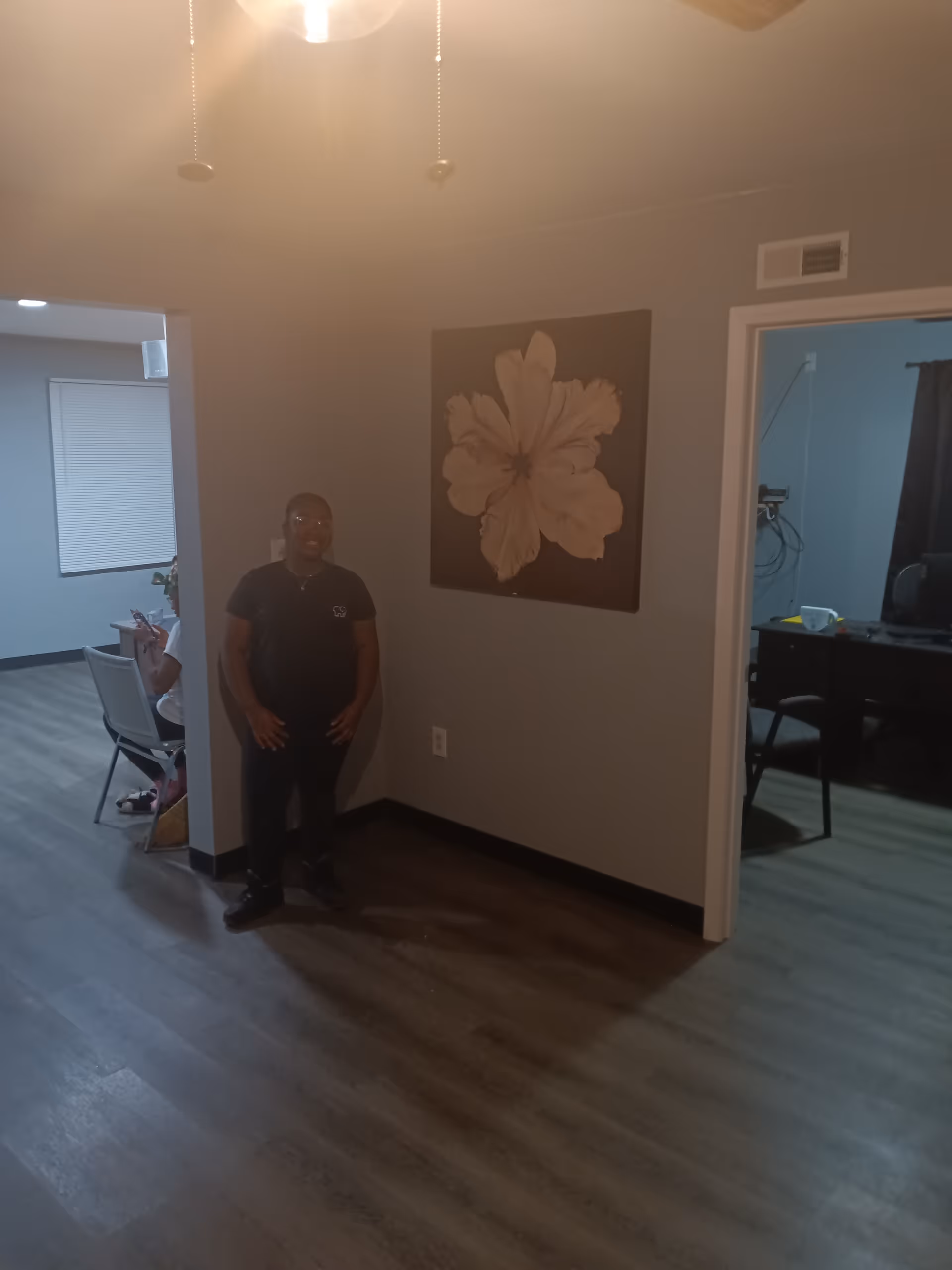 Man stands in an interior hallway with a large floral wall art.