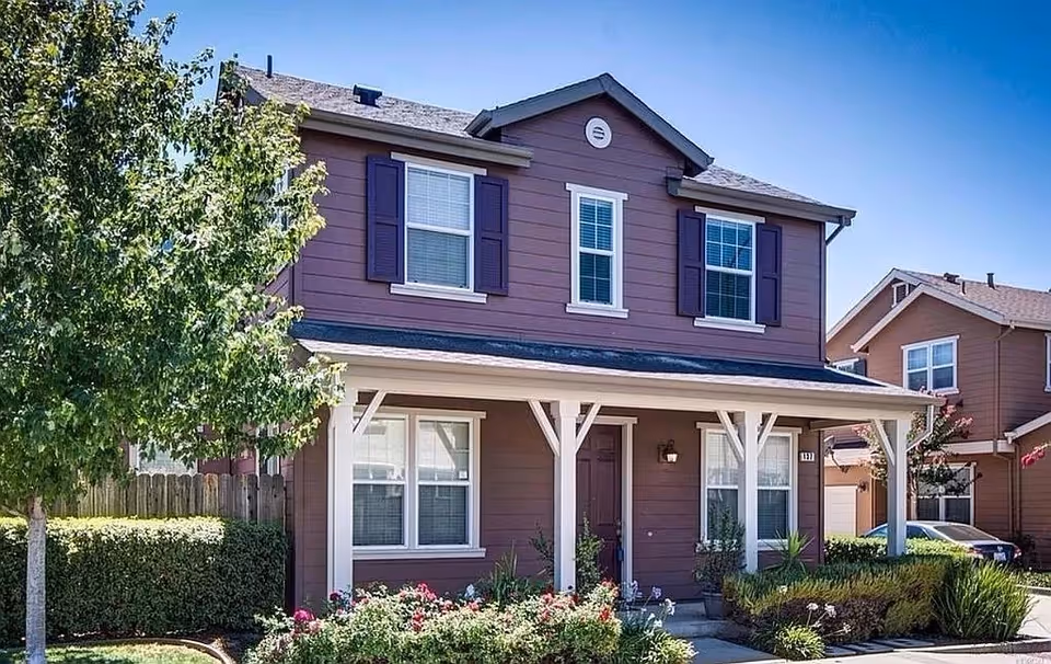 Brown two-story senior living home with a covered front porch and manicured landscaping.