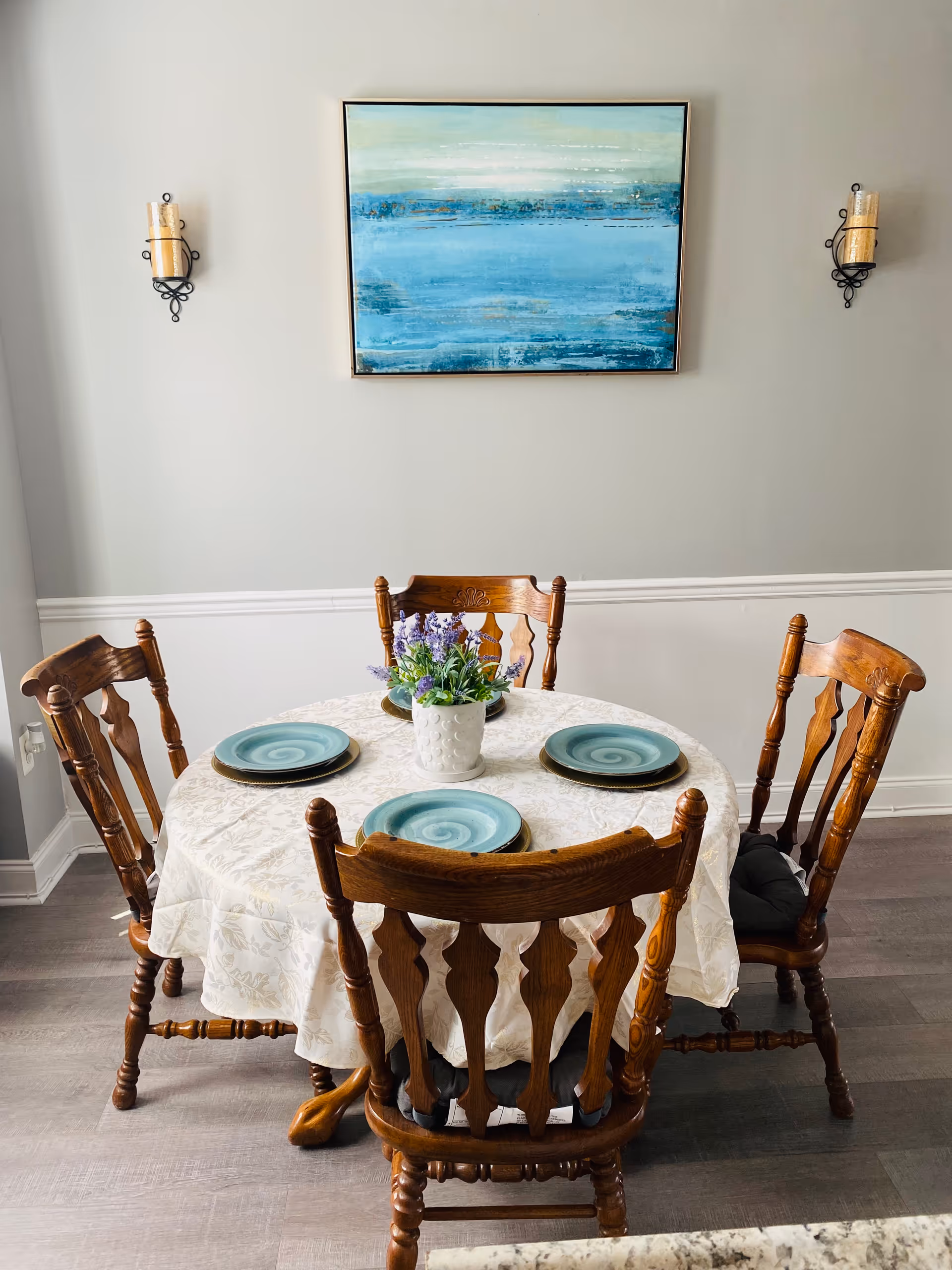 Round dining table with turquoise plates and wooden chairs in a bright dining room
