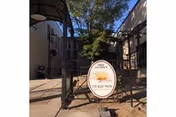 Gated outdoor entrance with a Sundance sign, flanked by building facades and trees.