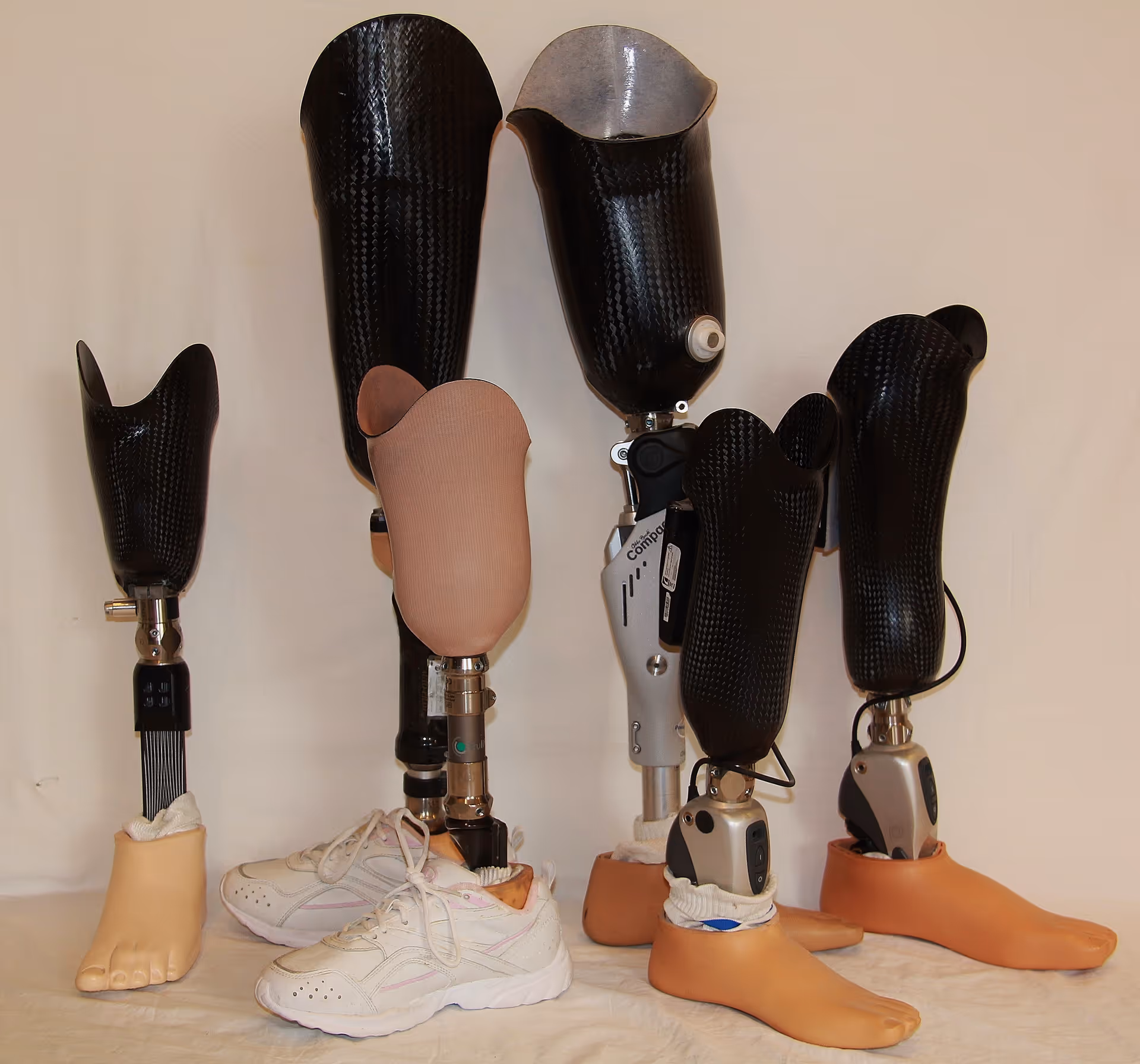 Several prosthetic limbs and feet arranged on a table in a clinical interior.