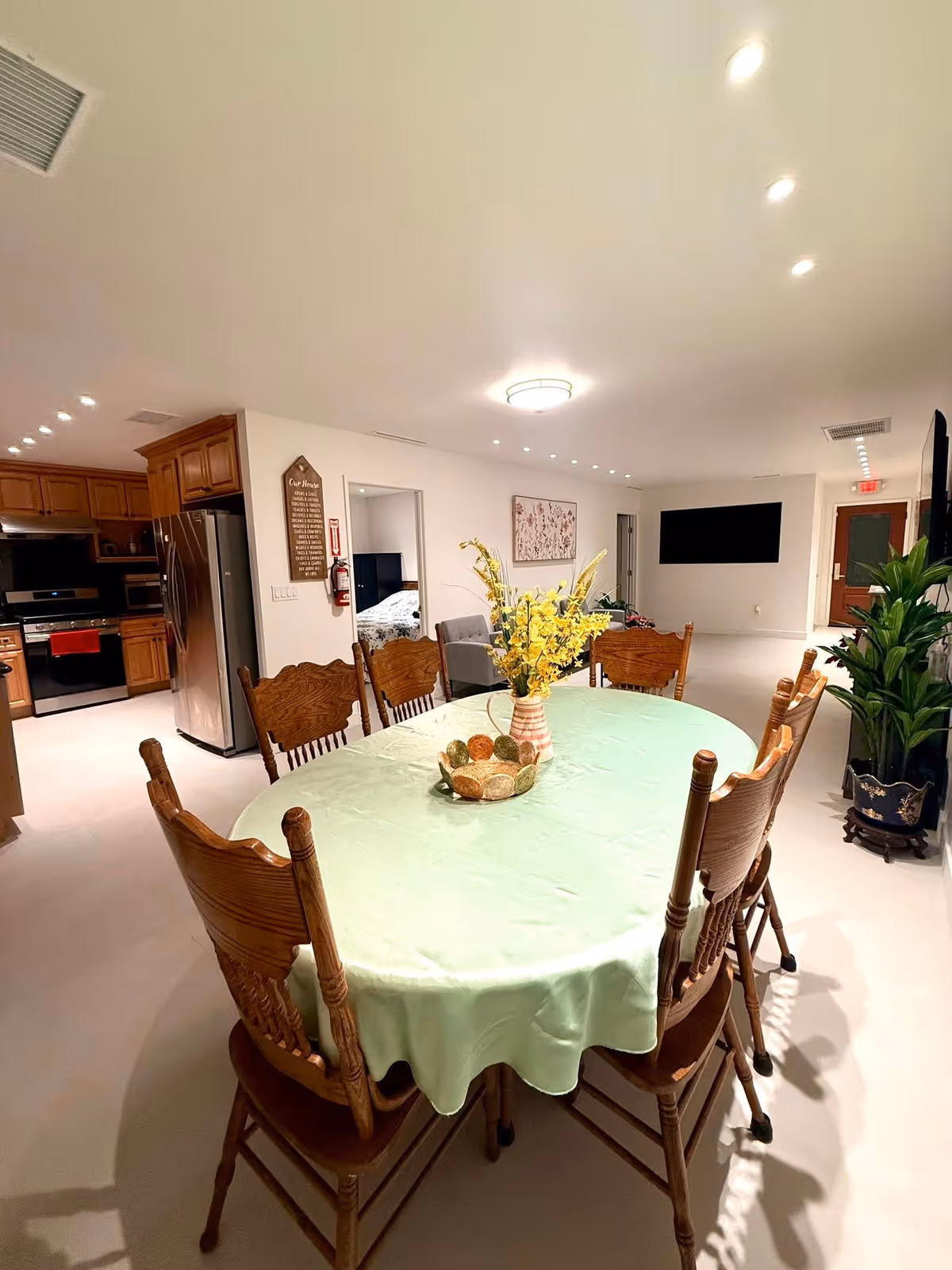 A large communal dining table with a pastel green tablecloth in a bright, airy room.