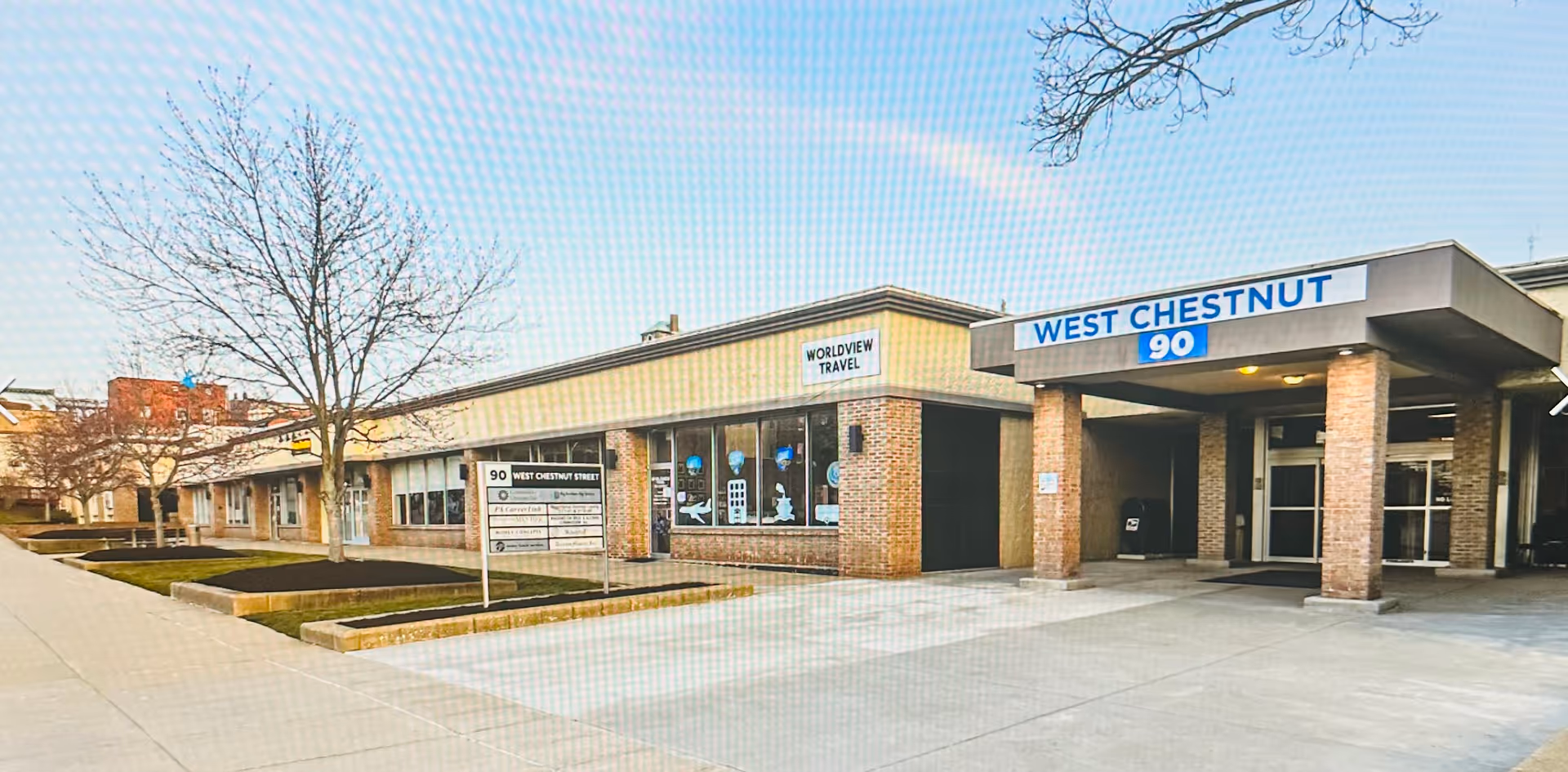 Exterior view of a single-story storefront building with Worldview Travel signage.
