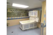 Interior room with a large medical device beside a mural wall.
