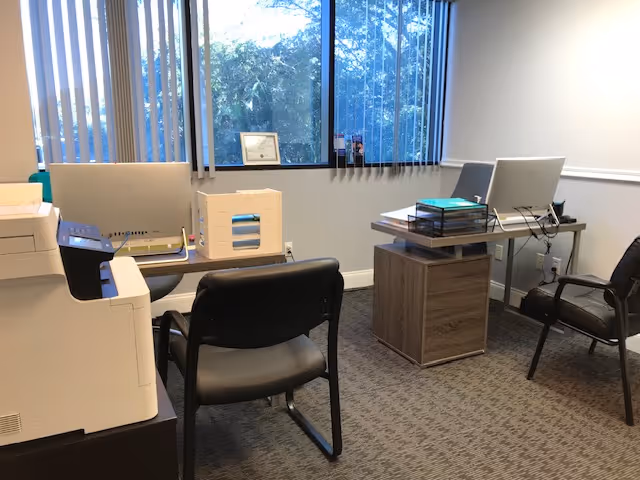 Office interior at Mazaltov In Home Care with desk, printer, and window blinds.