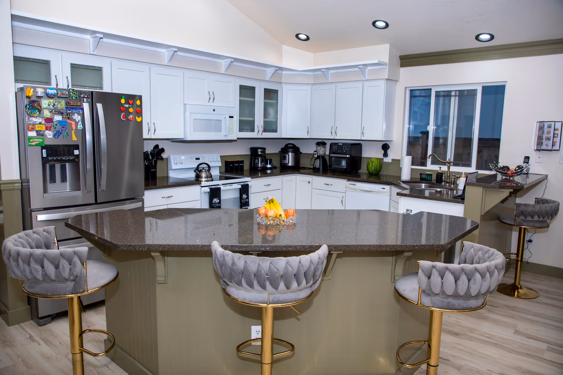 Modern communal kitchen with white cabinets, stainless appliances, and a large central island.