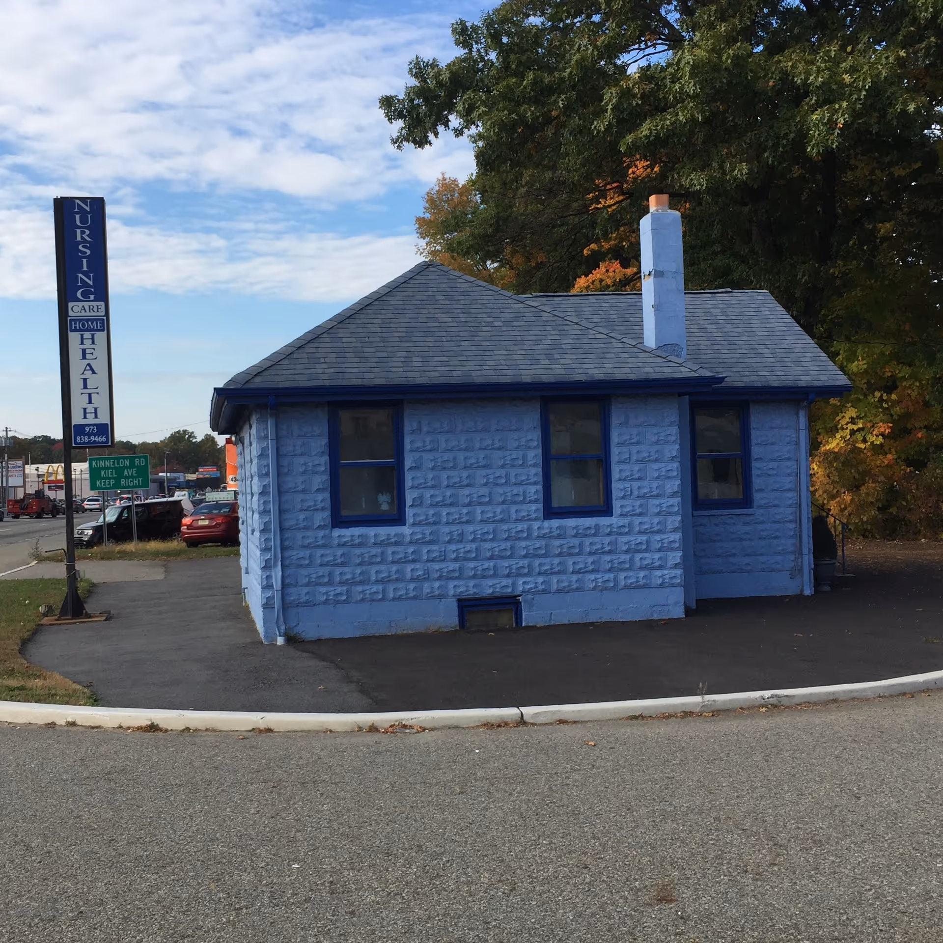 Small blue brick nursing care facility building with a vertical sign beside it
