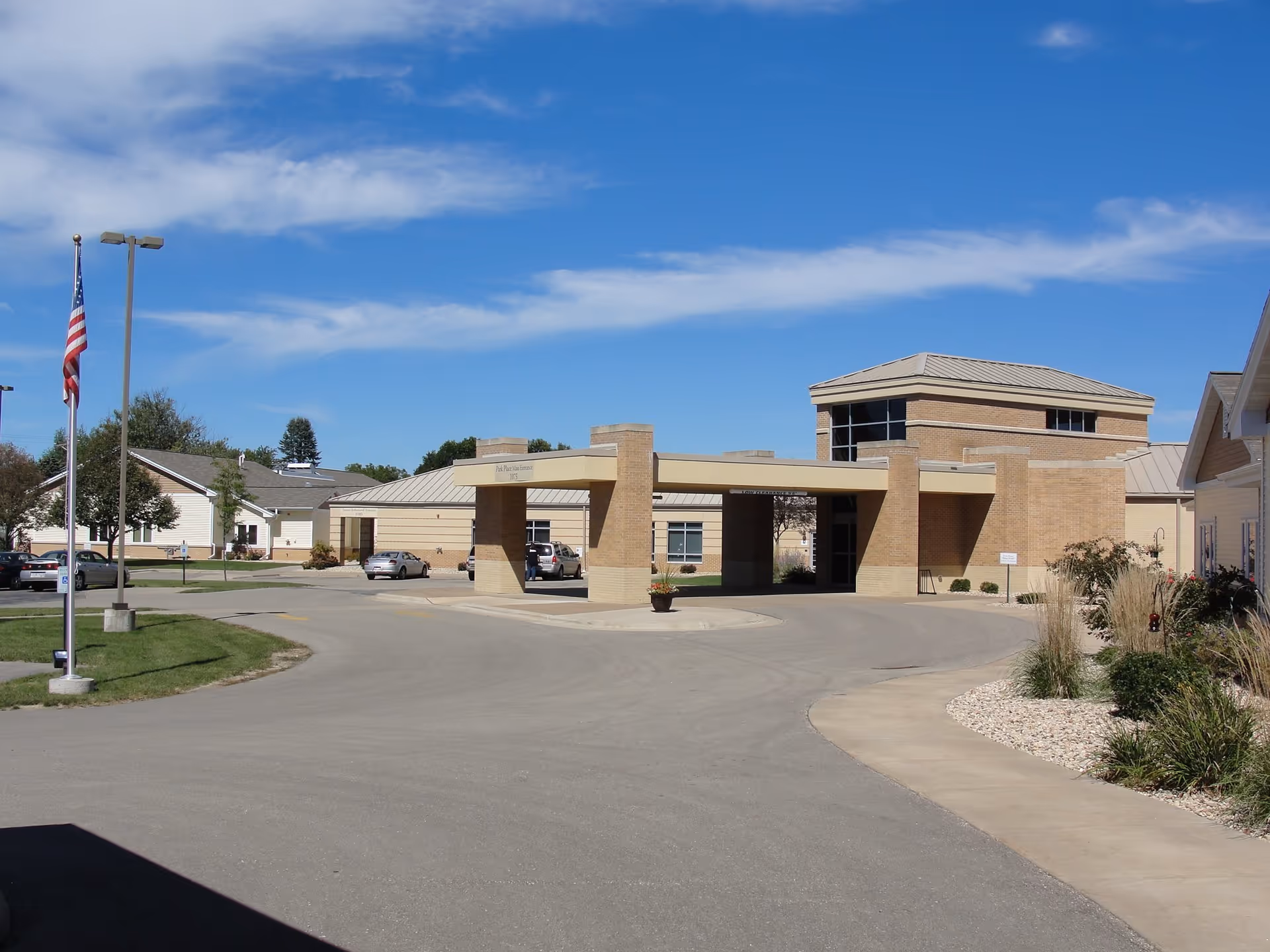 Exterior view of a Park Place Assisted Living entrance with a circular driveway and flagpole.