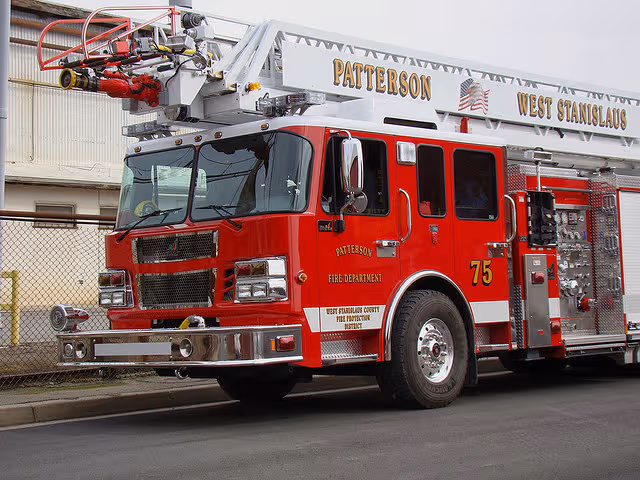 Red Patterson fire truck parked outside a building behind a chain-link fence.