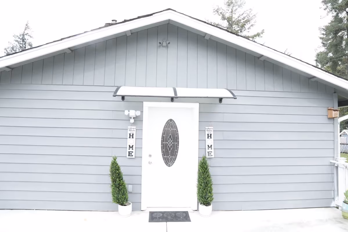 Bright Care AFH DesMoines LLC exterior with a white door and two potted evergreens.