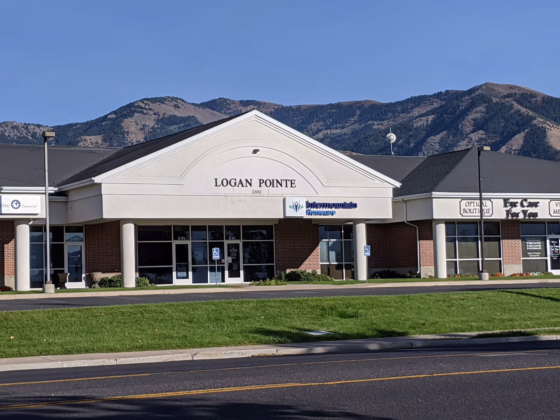 Front view of a strip mall with Logan Pointe and Intermountain Homecare storefronts, mountains behind.