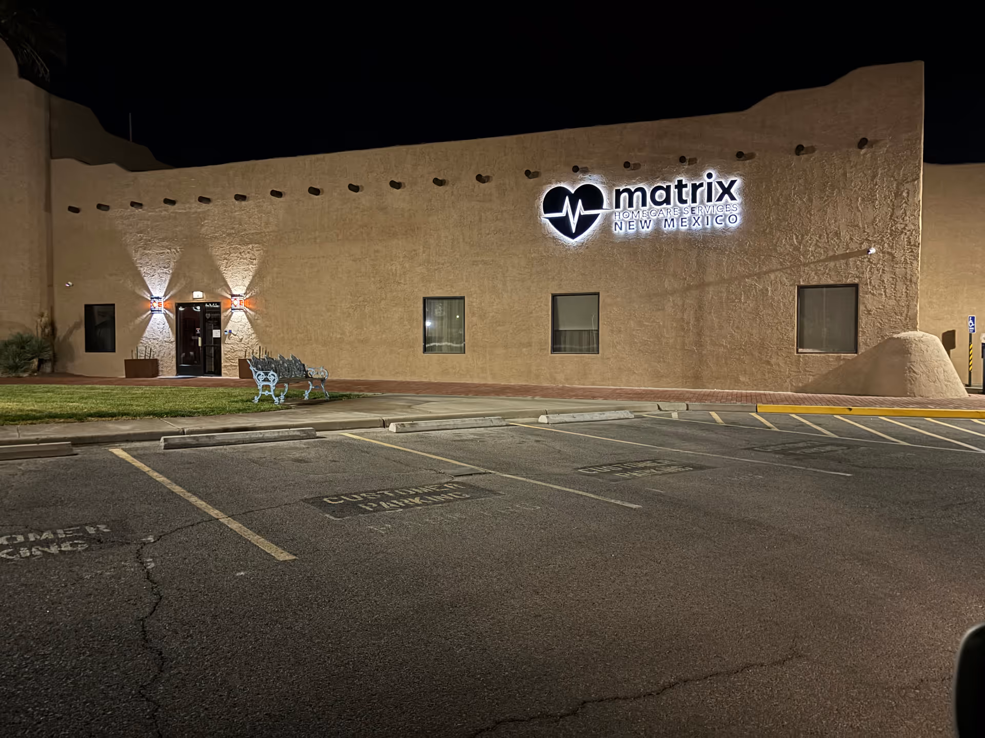 Exterior view of Matrix Home Care Services New Mexico building at night with parking lot.