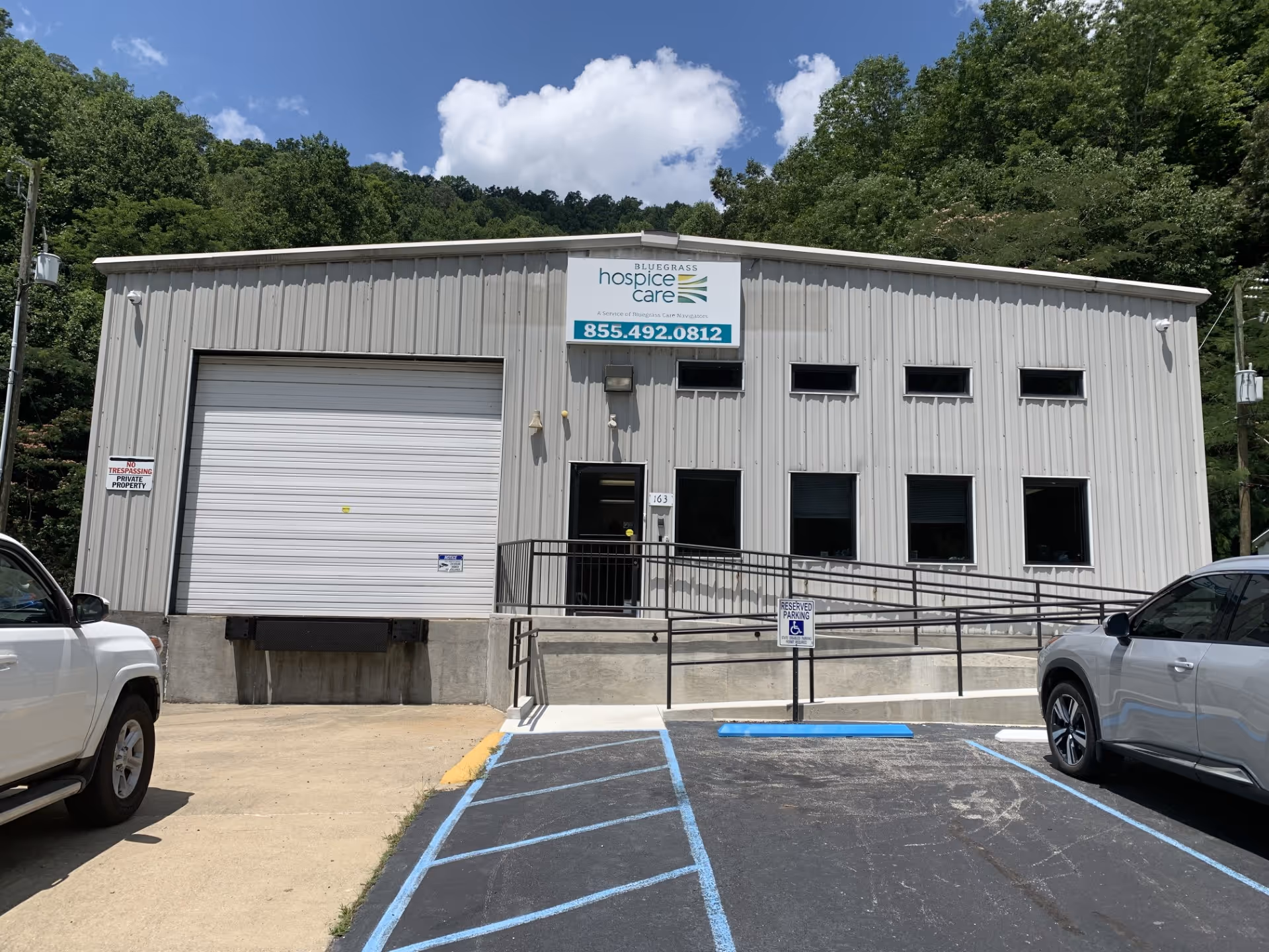 Front exterior of a gray metal facility building with ramp and parking.