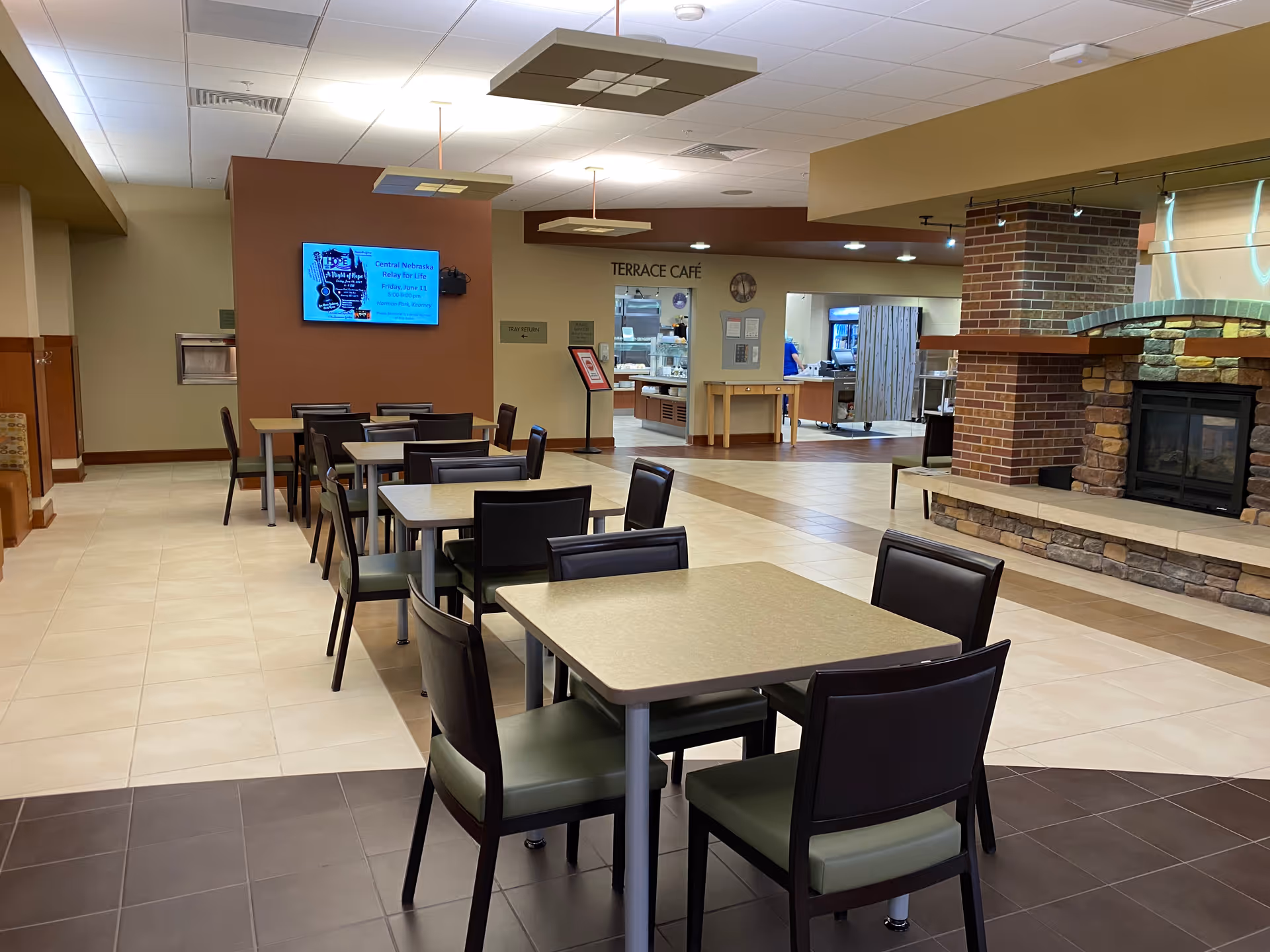 Interior view of a senior living facility dining area with tables, chairs, and a fireplace