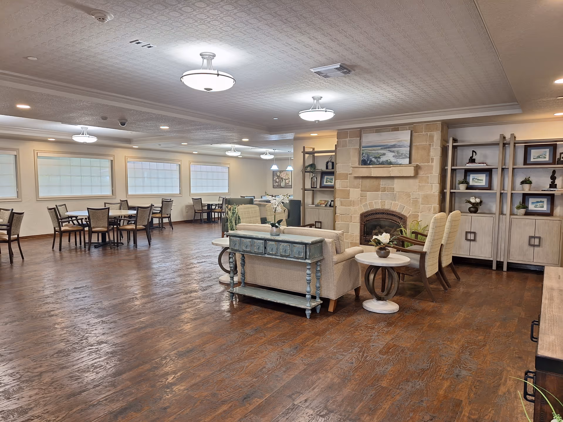 Spacious senior center lounge with sofas, tables, and a stone fireplace.