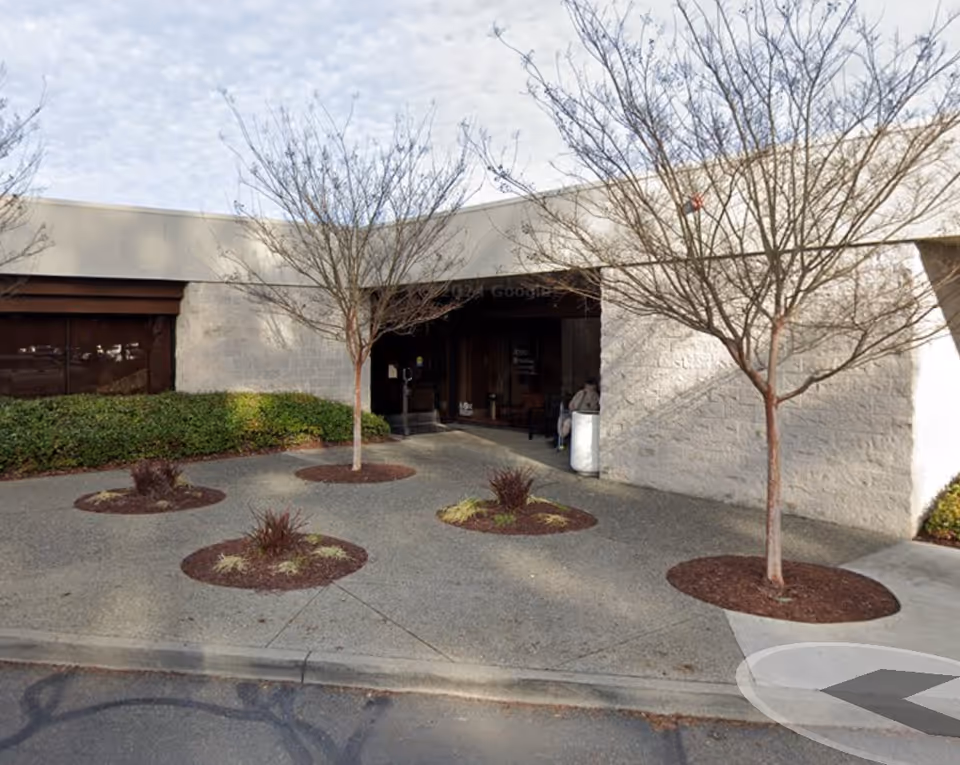 Exterior entrance to Hillendale Home Care with trees, circular mulch beds, and a doorway.