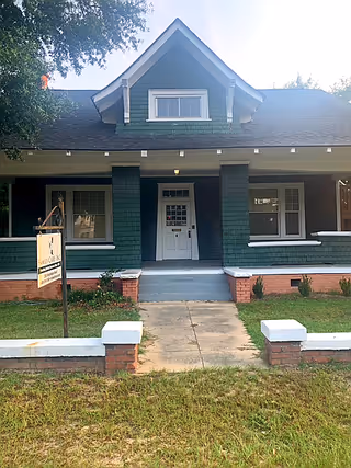 Front view of teal colored, single-story senior care facility with a porch.