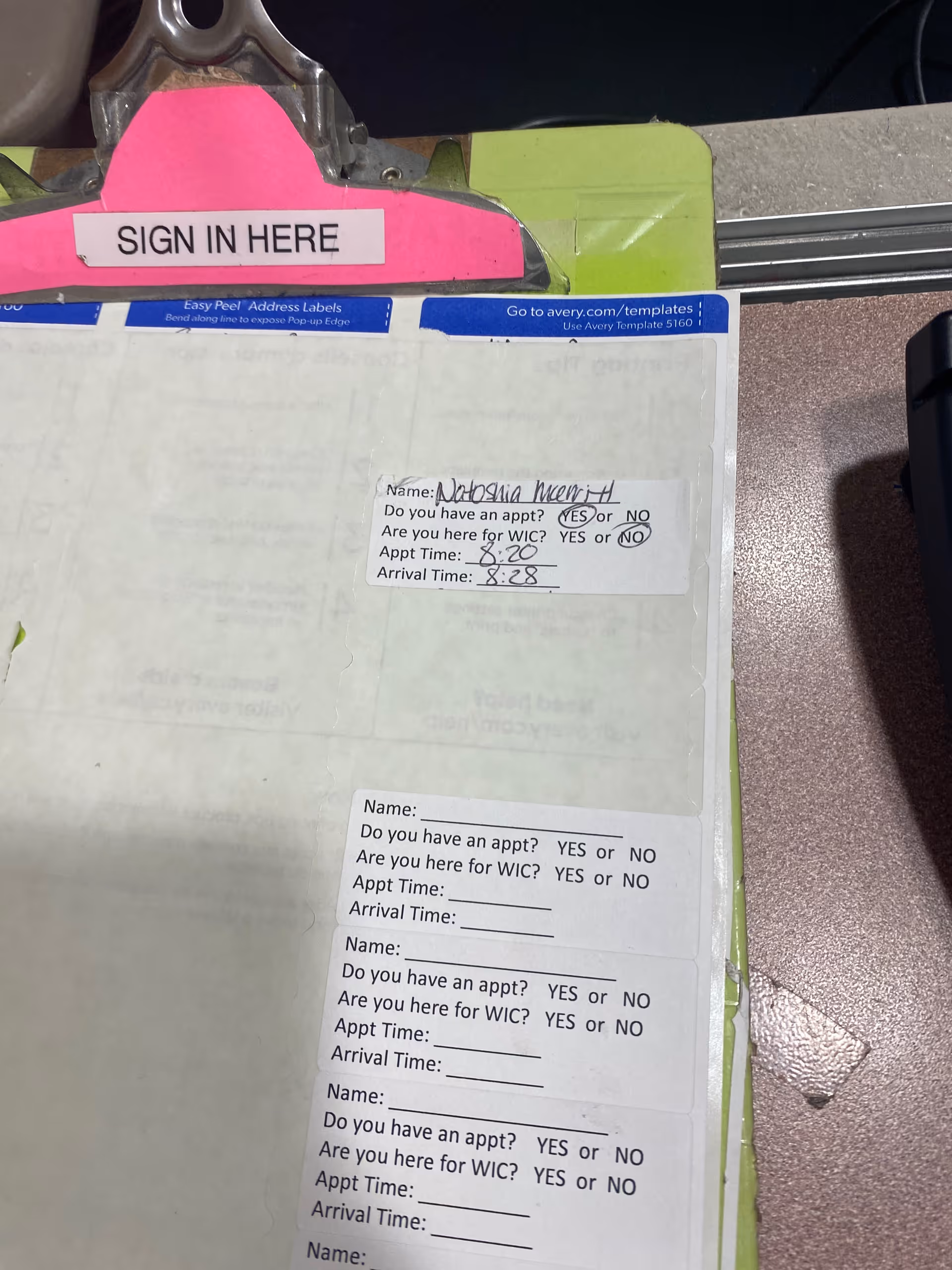 Clipboard with Sign In Here tab and appointment forms on a counter.